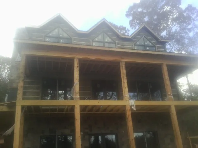 Dormers and porch framing on a large log home under construction — Roof Coating work by our crew in Boonville